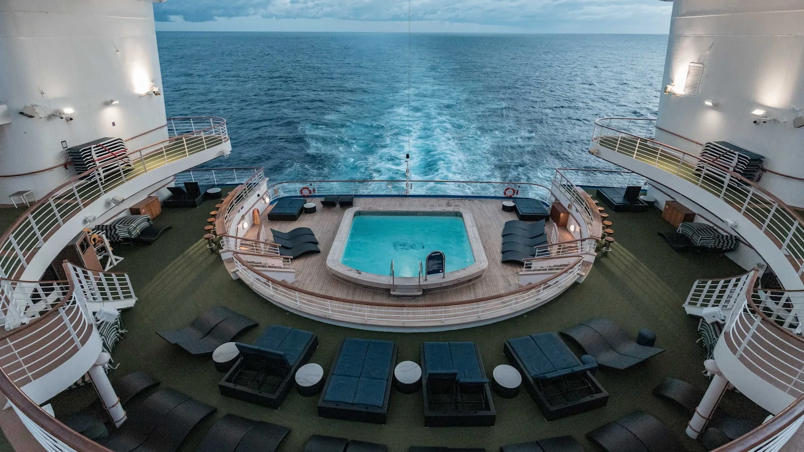 Outdoor swimming pool on a cruise ship deck with sun loungers and clear blue sky