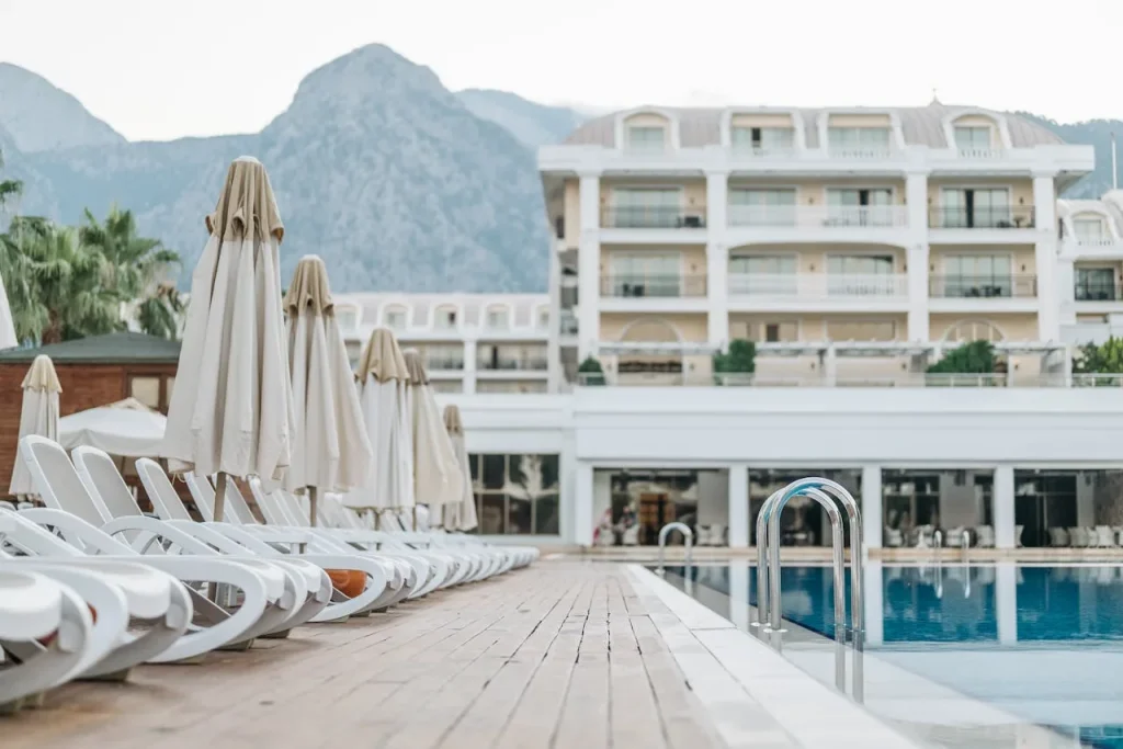 A luxury hotel outdoor swimming pool surrounded by sun loungers umbrellas and palm trees under a blue sky representing the Bellagio pool complex in Las Vegas with five Mediterranean-style pools and private cabanas