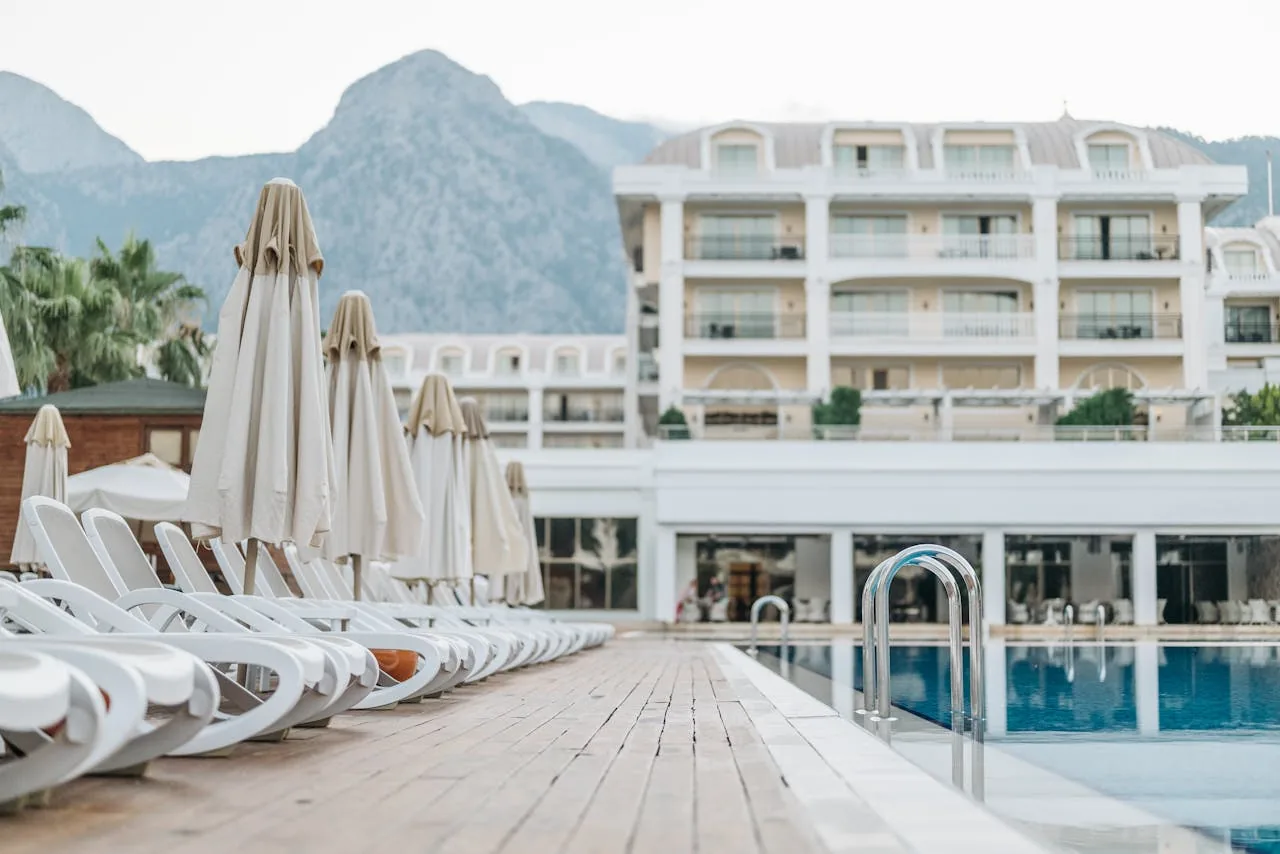 A luxury hotel outdoor swimming pool surrounded by sun loungers umbrellas and palm trees under a blue sky representing the Bellagio pool complex in Las Vegas with five Mediterranean-style pools and private cabanas