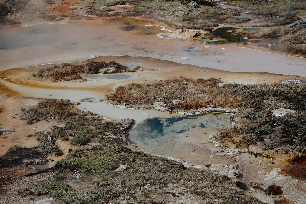 Natural geothermal hot springs with mineral-coloured pools and volcanic terrain representing New Zealand geothermal landscape and the thermal spring activity underlying NZ thermal pool destinations including Rotorua and Hanmer Springs