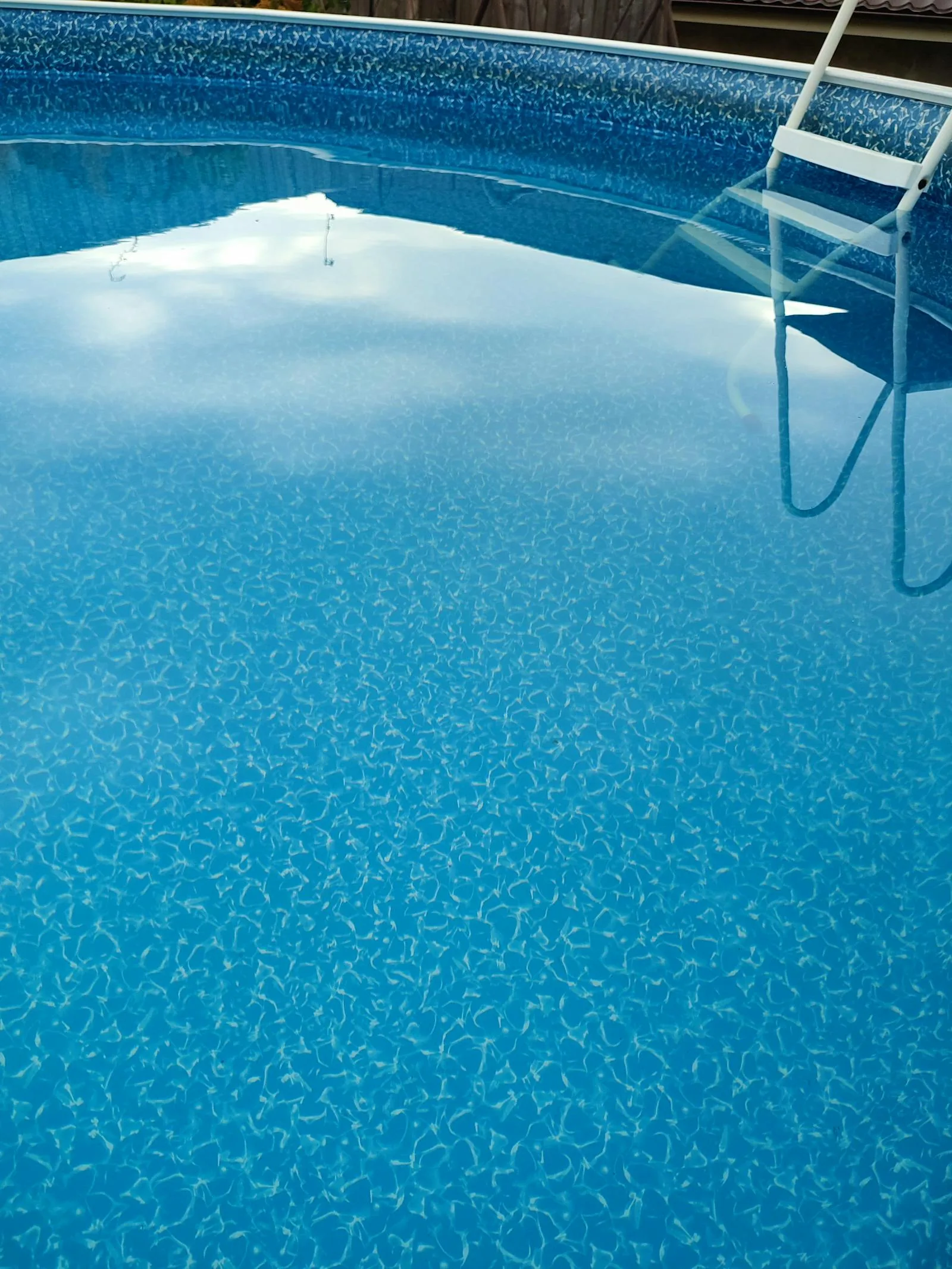 Above ground circular swimming pool with blue patterned liner and white entry ladder
