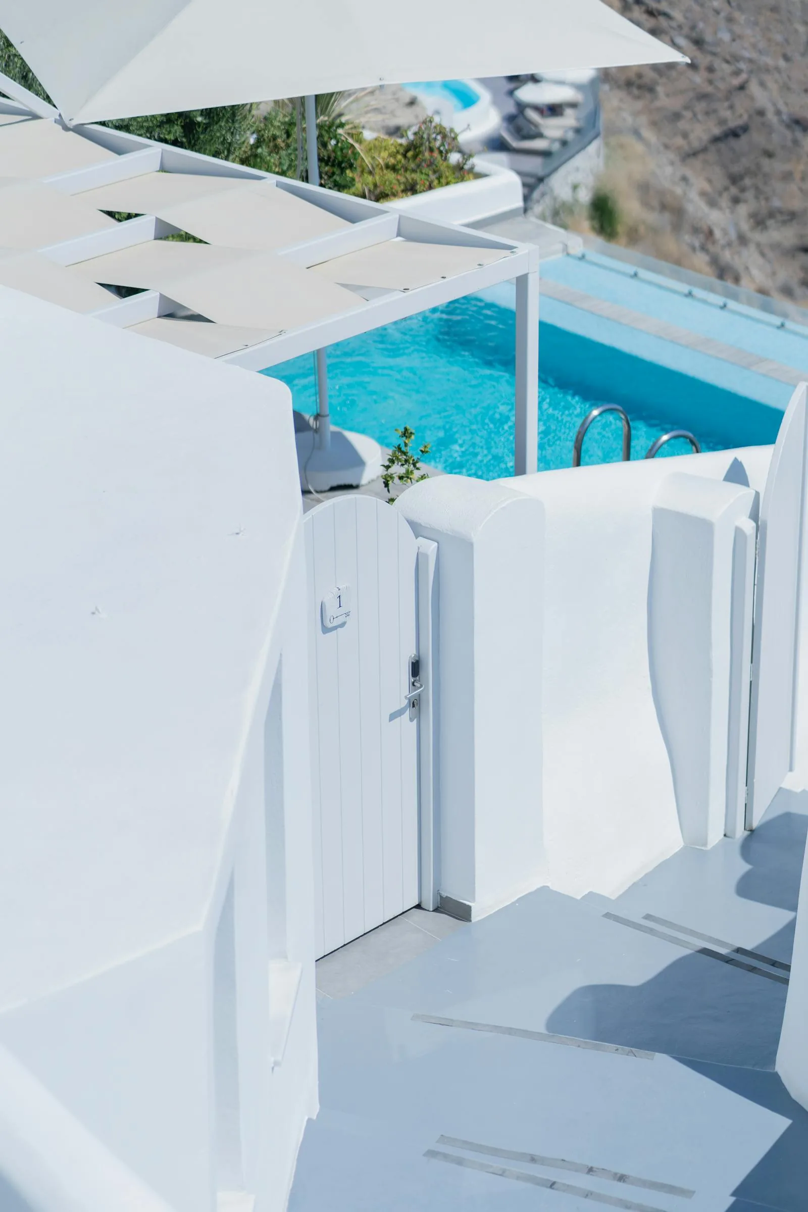 A private infinity plunge pool on a whitewashed cliff-edge terrace in Santorini with views across the blue Aegean Sea and volcanic Caldera, representing the luxury private pool suite hotels in Oia Santorini
