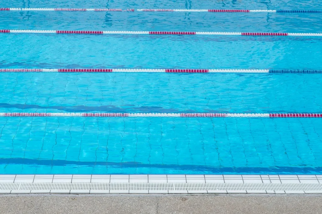 Clear blue outdoor swimming pool with lane dividers and red and white lane ropes — competition outdoor pool in Essex