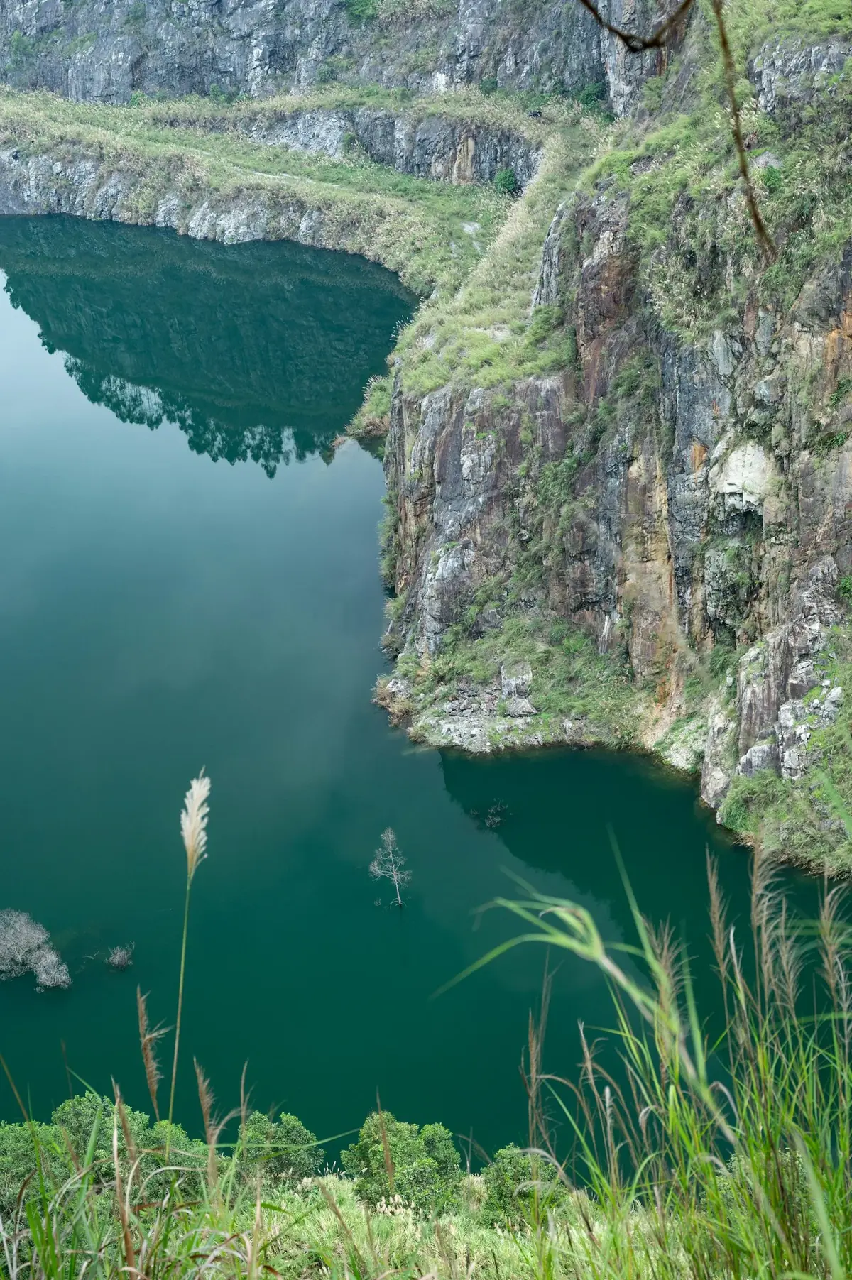 A vivid turquoise blue flooded quarry surrounded by limestone cliffs and moorland