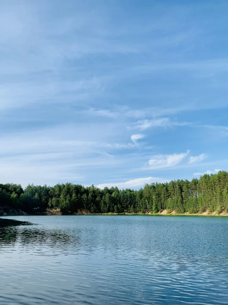 A vivid turquoise blue natural lake surrounded by pine forest — illustrating the striking colour of the UK's most famous blue pools