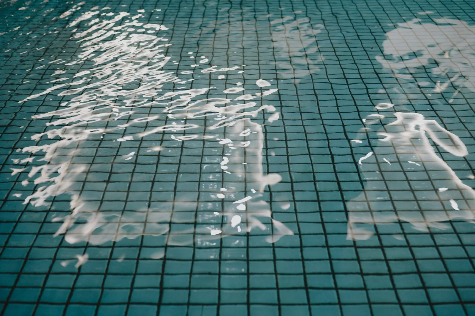 Swimmer's reflection in a tiled indoor pool, illustrating pool water exposure