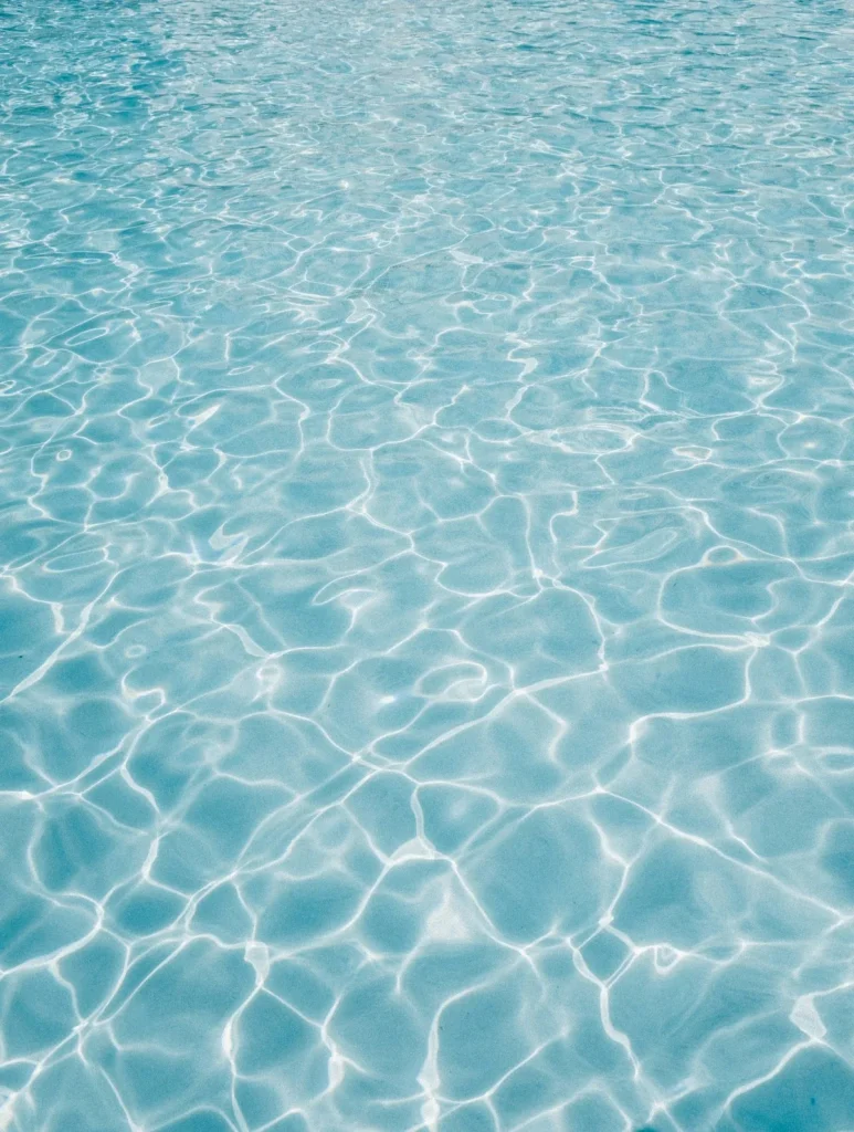 Close-up of clear blue chlorinated swimming pool water with light ripples on the surface, representing the question of whether pool water can cause or transmit thrush (Candida yeast infection)