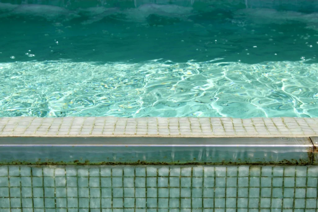 Close-up of clear turquoise swimming pool water at the pool edge showing mosaic tile coping