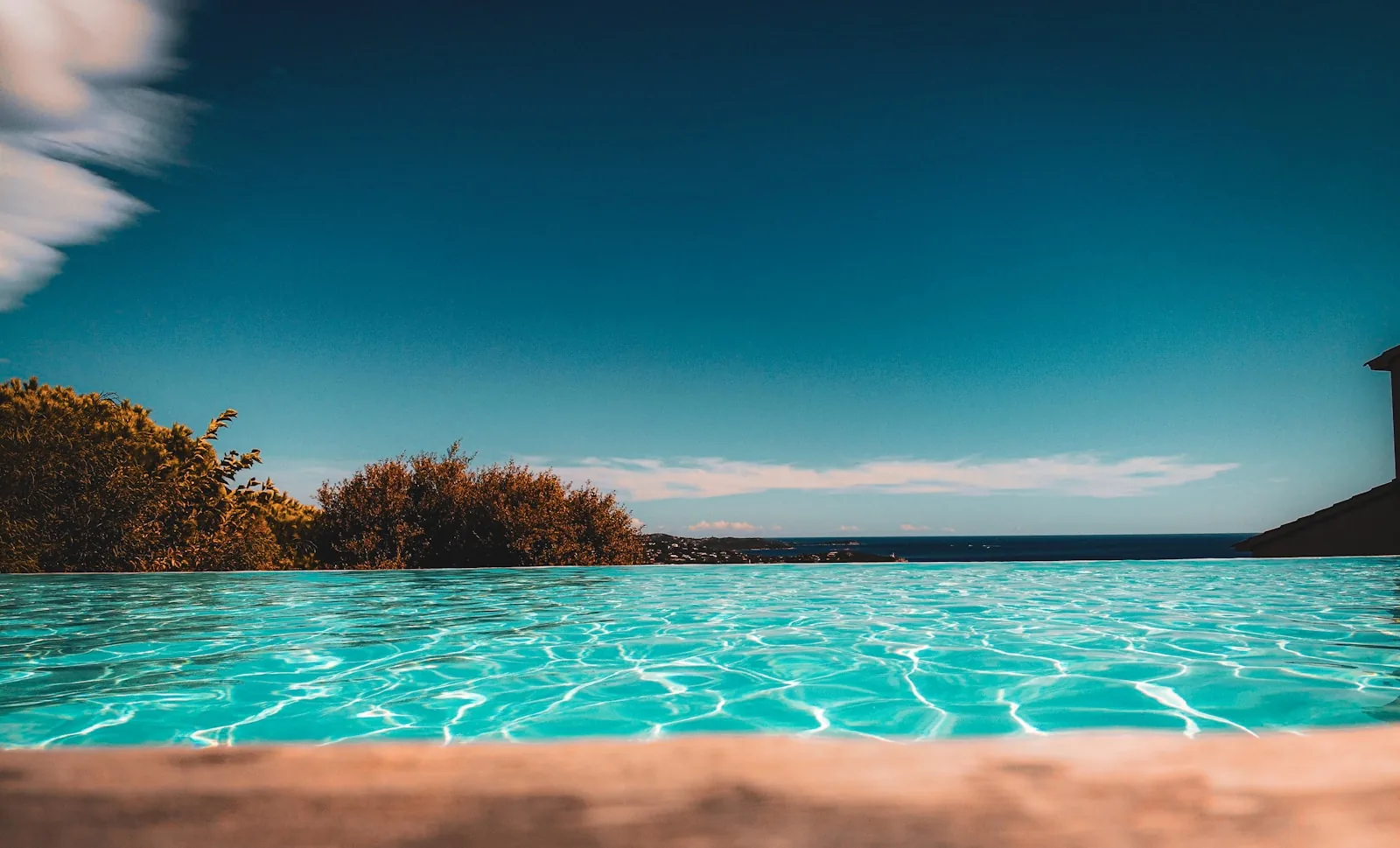 Infinity pool with clear blue water overlooking the sea and sky on a sunny day in Corsica