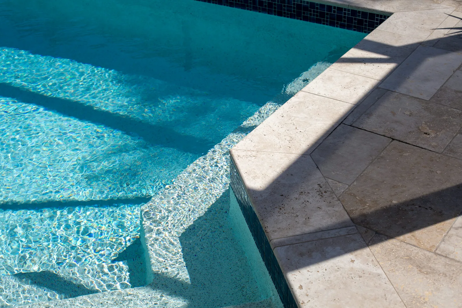 Clear turquoise pool water lapping at stone coping tiles