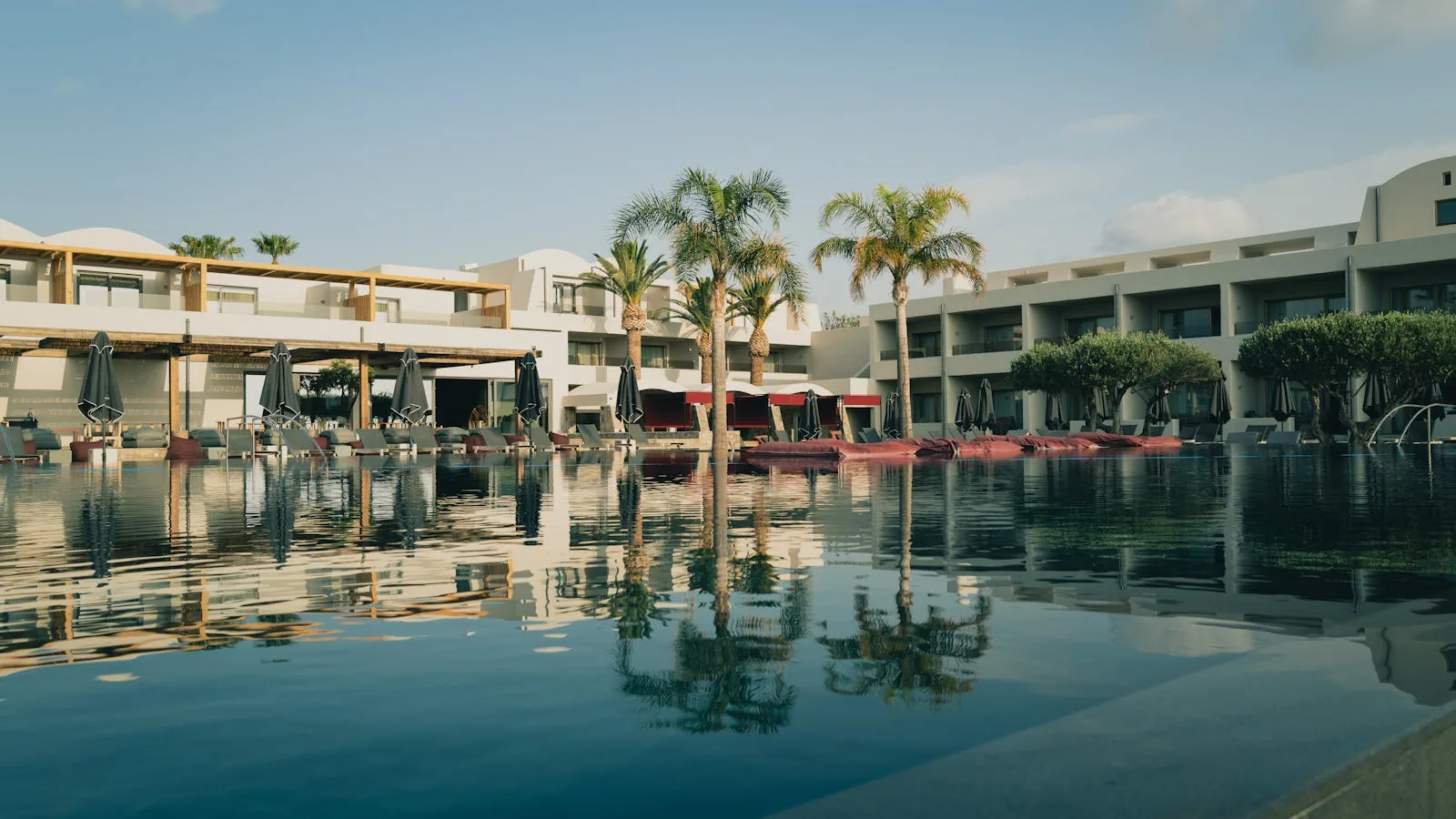 A rectangular outdoor swimming pool surrounded by lush Mediterranean garden with sun loungers and parasols at a boutique hotel in Dubrovnik Croatia, representing the mid-range and boutique pool hotel options in Dubrovnik