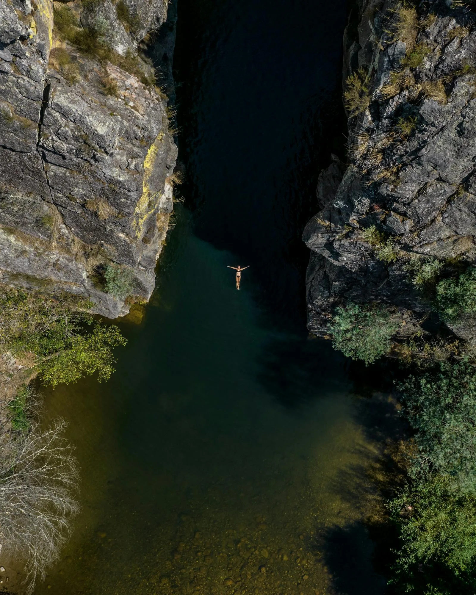 Aerial view of a wild swimmer floating on their back in a natural rocky pool