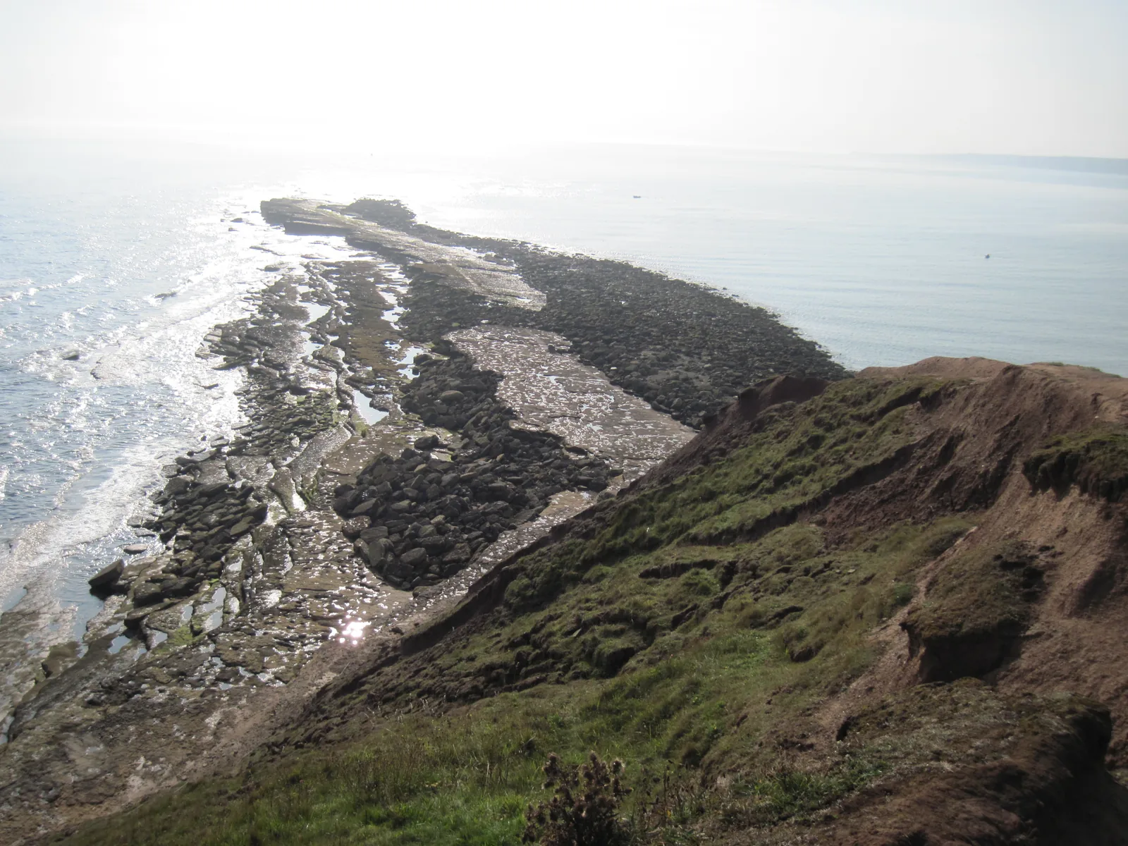 Elevated view of Filey Brigg's rocky intertidal platform at low tide in early morning light, showing water-filled channels and rock pools, Yorkshire coast