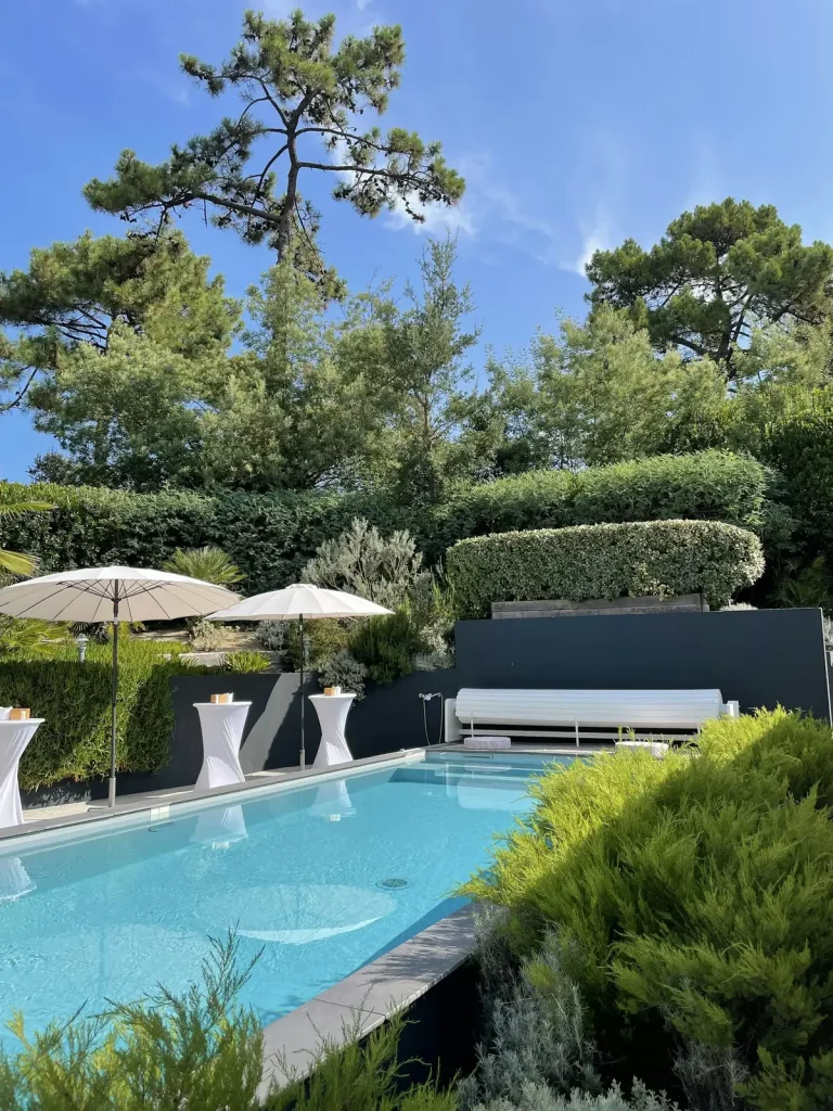 Modern outdoor swimming pool with Mediterranean pine trees and parasols representing a private pool in a French villa rental