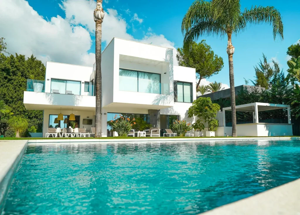A modern luxury holiday villa with a large private swimming pool surrounded by palm trees and lush garden representing Greek island villa pool holidays on Corfu Kefalonia and the Ionian islands