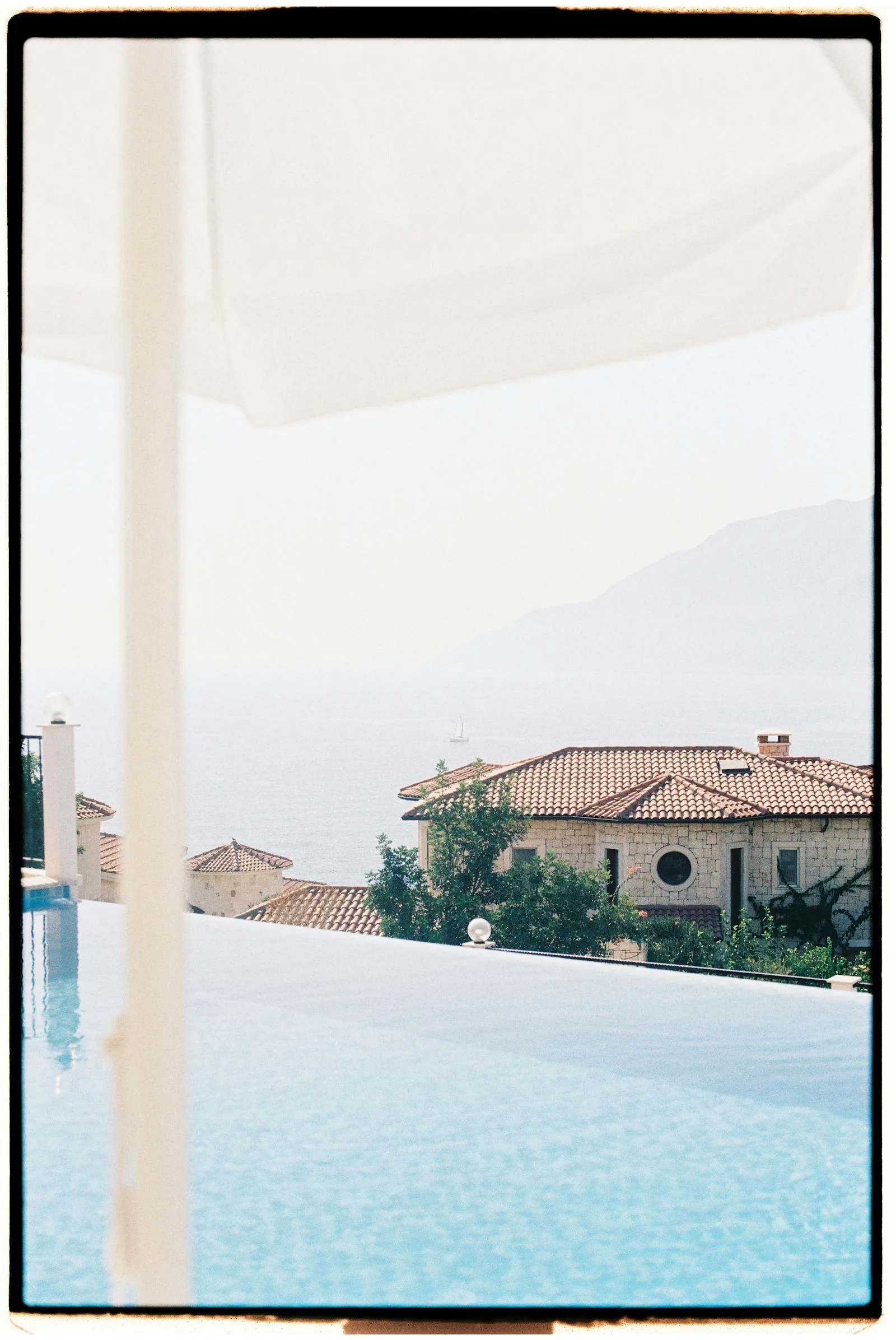 A private garden swimming pool at a Greek villa holiday with clear blue water sun loungers and parasols surrounded by stone paving and lush Mediterranean vegetation representing what to expect from a Greek villa pool holiday