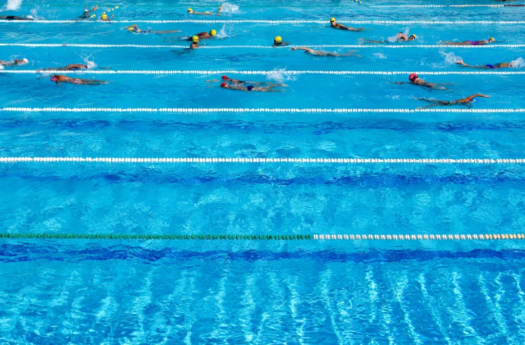 Overhead view of swimmers in a multi-lane swimming pool with lane ropes