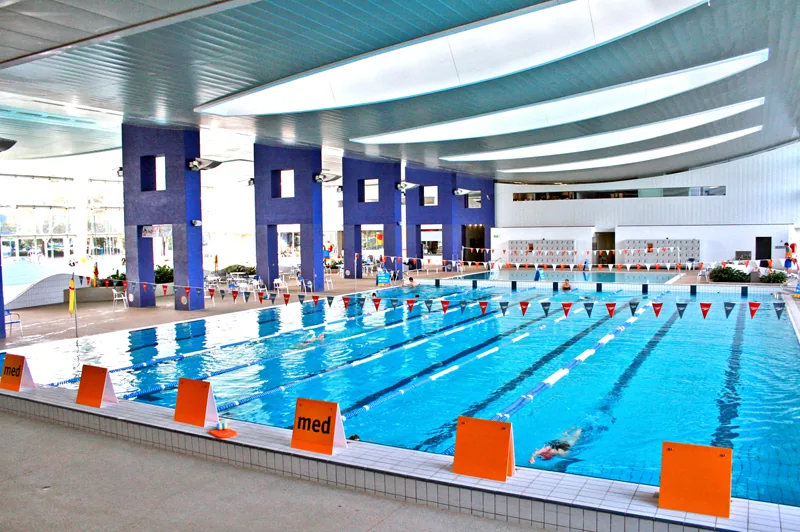 Indoor public leisure centre swimming pool with lane markings and modern architecture