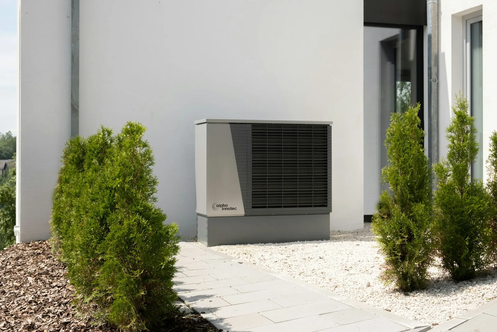Air-source heat pump unit installed beside an inground swimming pool in a UK garden