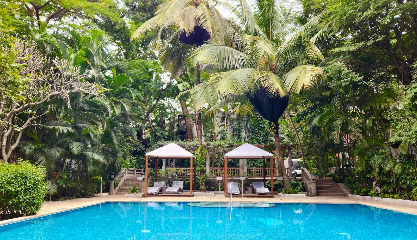 A heated outdoor swimming pool at a UK hotel or country house resort with sun loungers and manicured garden grounds under a clear sky representing UK hotels with outdoor pools by region