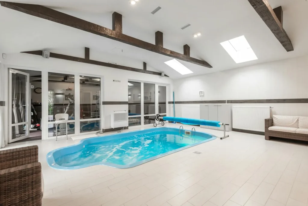 Indoor private swimming pool in a UK house with exposed wooden beam ceiling and natural skylights
