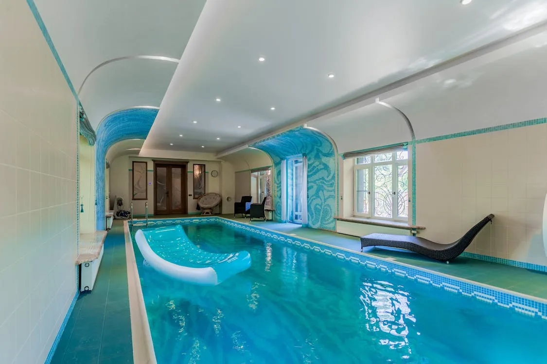 Indoor private swimming pool at a UK holiday house rental with blue water and poolside loungers