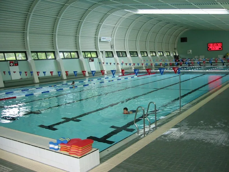 Interior of a UK public leisure centre swimming pool showing lane dividers and the characteristic curved barrel-vault roof