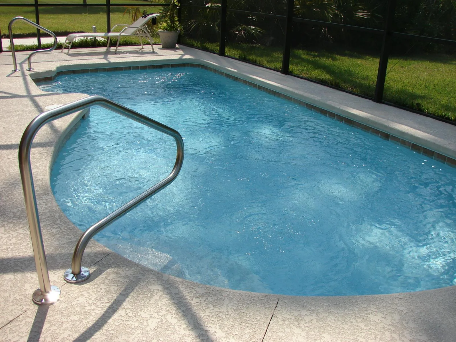 A newly installed inground swimming pool in a UK garden with blue water and paving surround