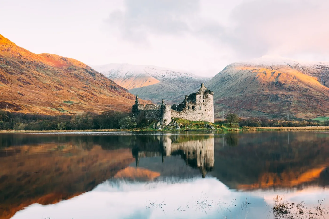 Kilchurn Castle reflected in the still waters of Loch Awe with golden autumn mountains in the background, Scotland