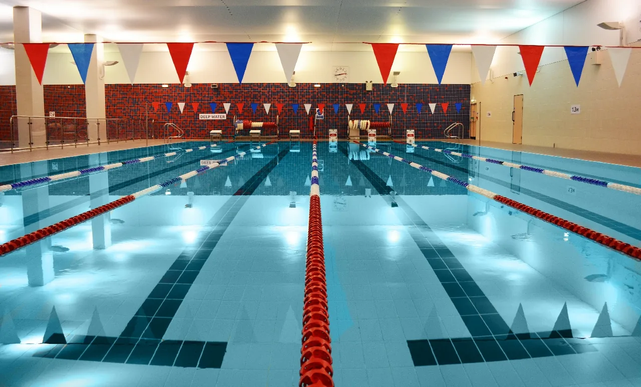 Indoor 25-metre swimming pool with lane ropes and bunting at a UK leisure centre