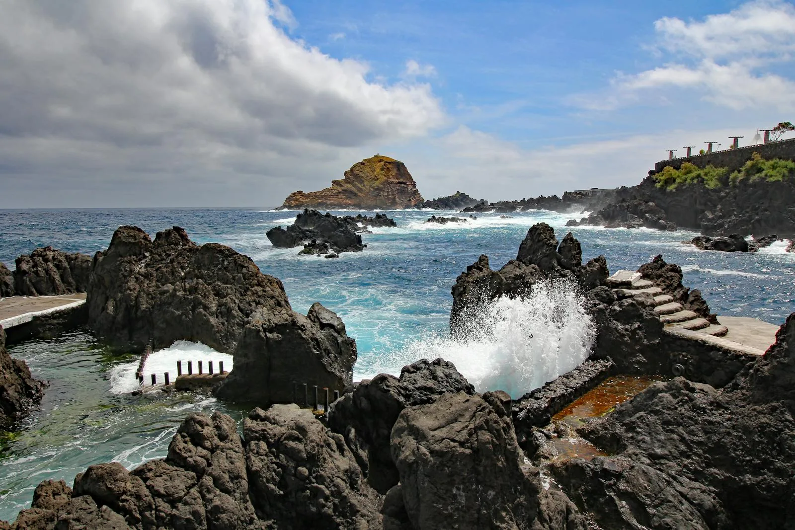 Swimmer in a clear turquoise volcanic rock pool in Madeira Portugal with black lava rock surround