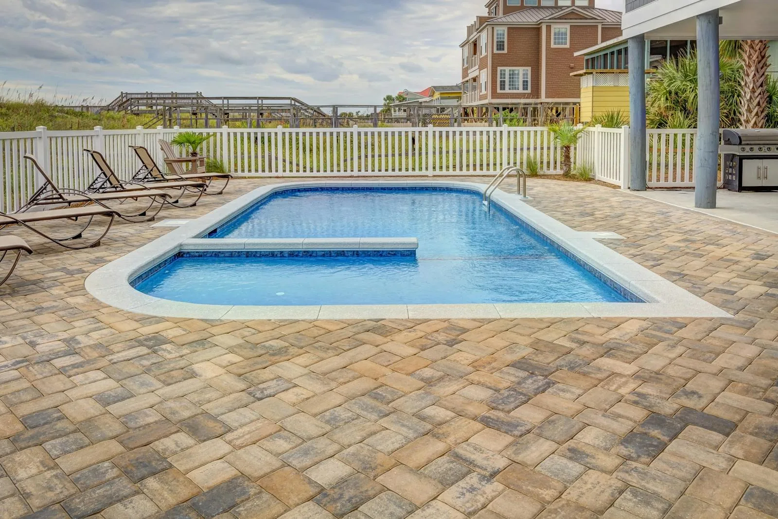 Outdoor swimming pool with sun loungers and paving