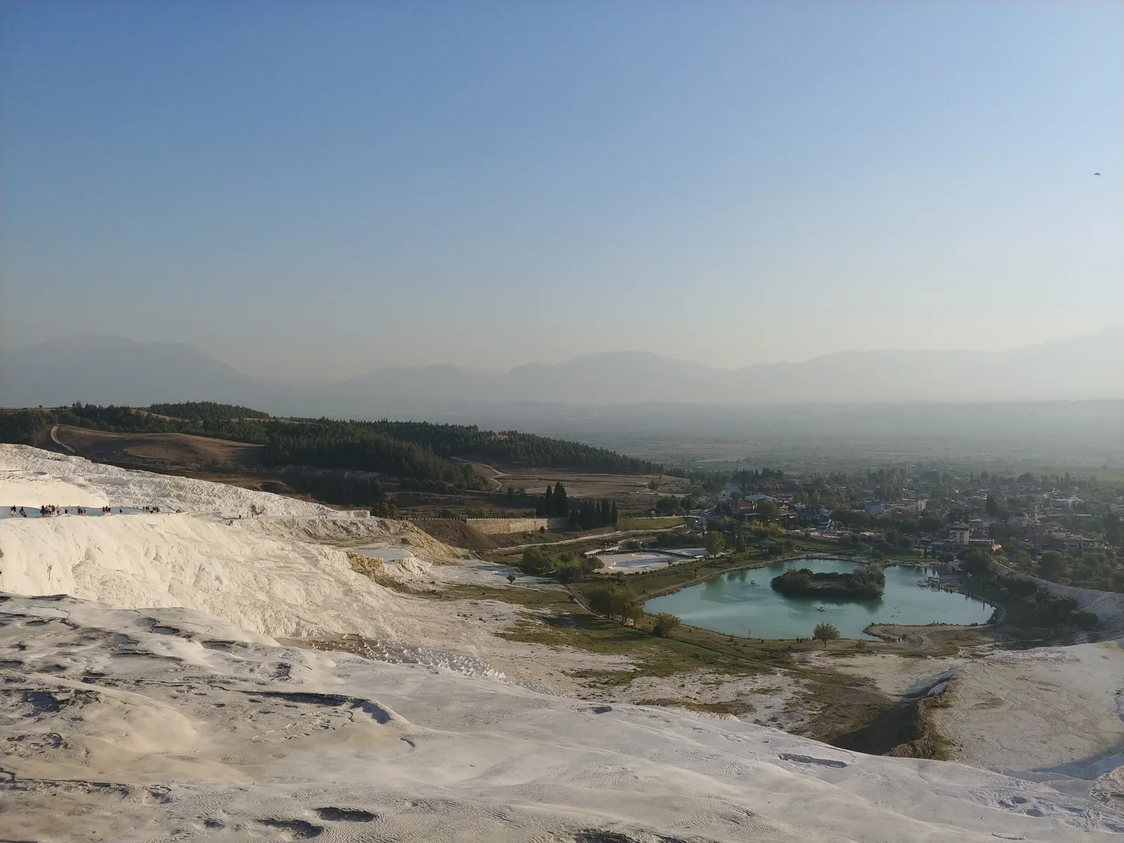 Aerial view of Pamukkale white terraces with the turquoise Cleopatra pool area and Pamukkale village below