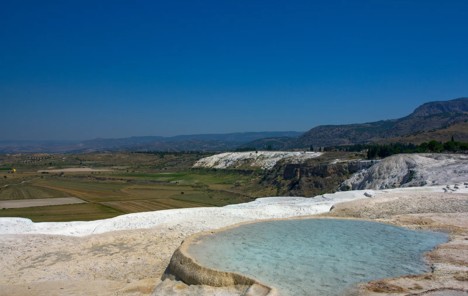 Single travertine pool at Pamukkale with the Denizli valley and Anatolian countryside in the background