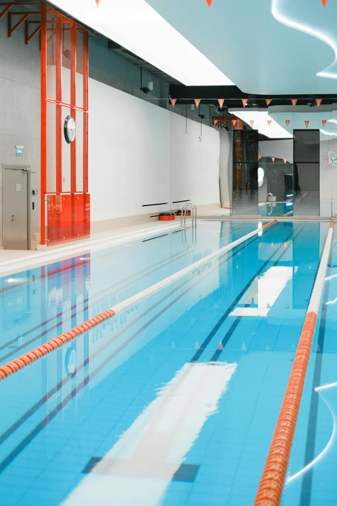 An indoor public swimming pool with lane ropes and blue water representing The Pools Swimming and Health Centre on James Street Carlisle Cumbria with three heated pools and Victorian Turkish Health Suite