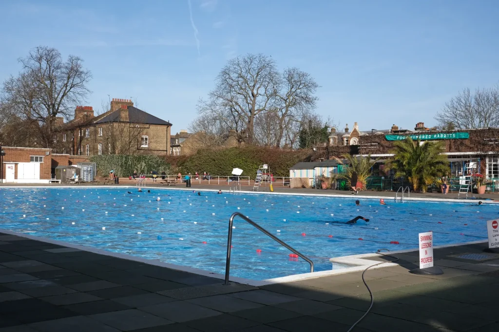 Brockwell Lido heated outdoor pool in Herne Hill London with lane swimmers and swimming lessons in progress