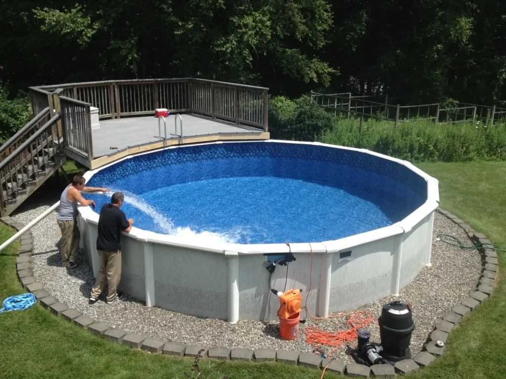 Workers installing a round steel-wall above-ground swimming pool with filter pump