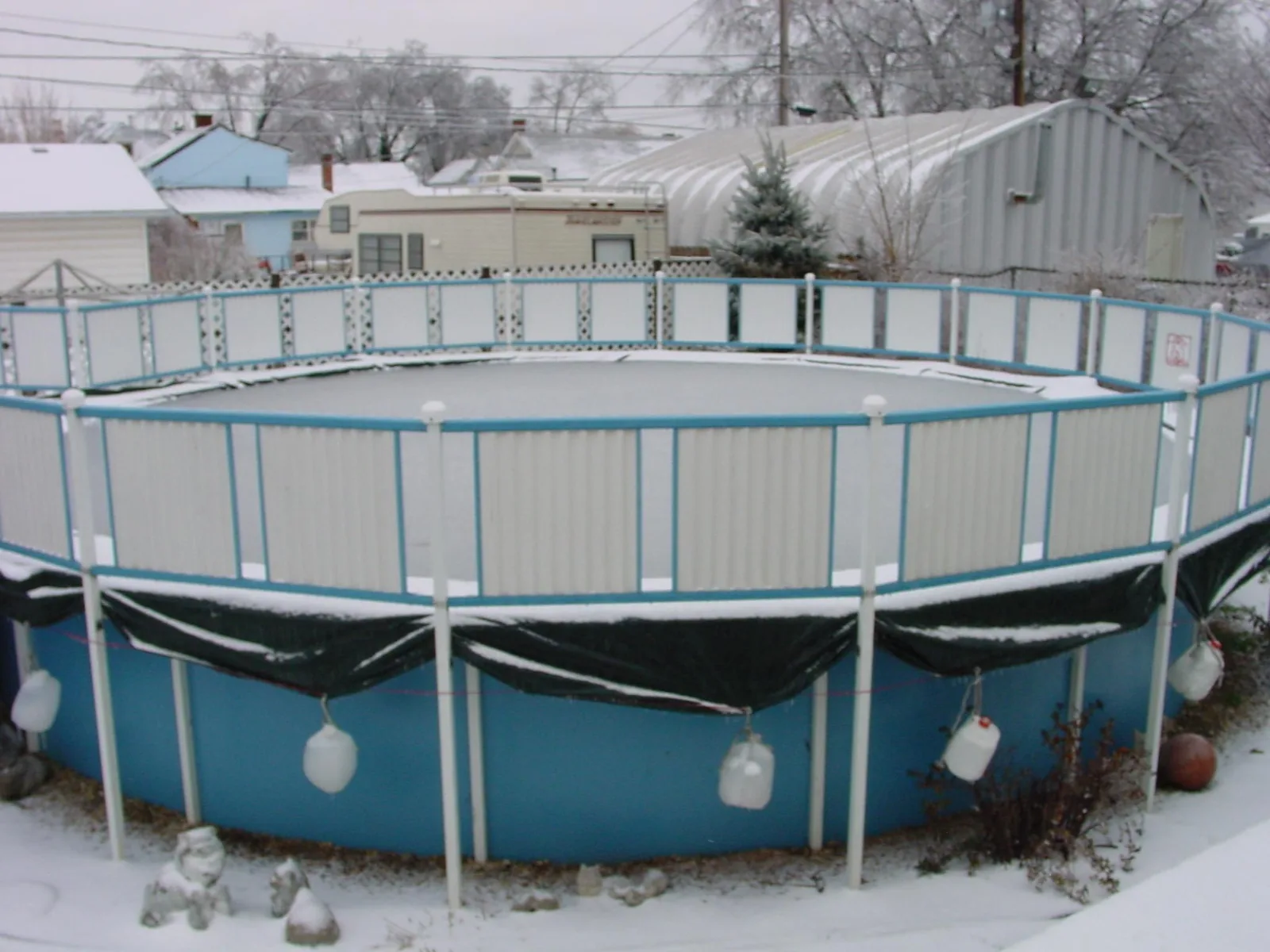 Round above-ground pool with winter cover in a residential backyard garden