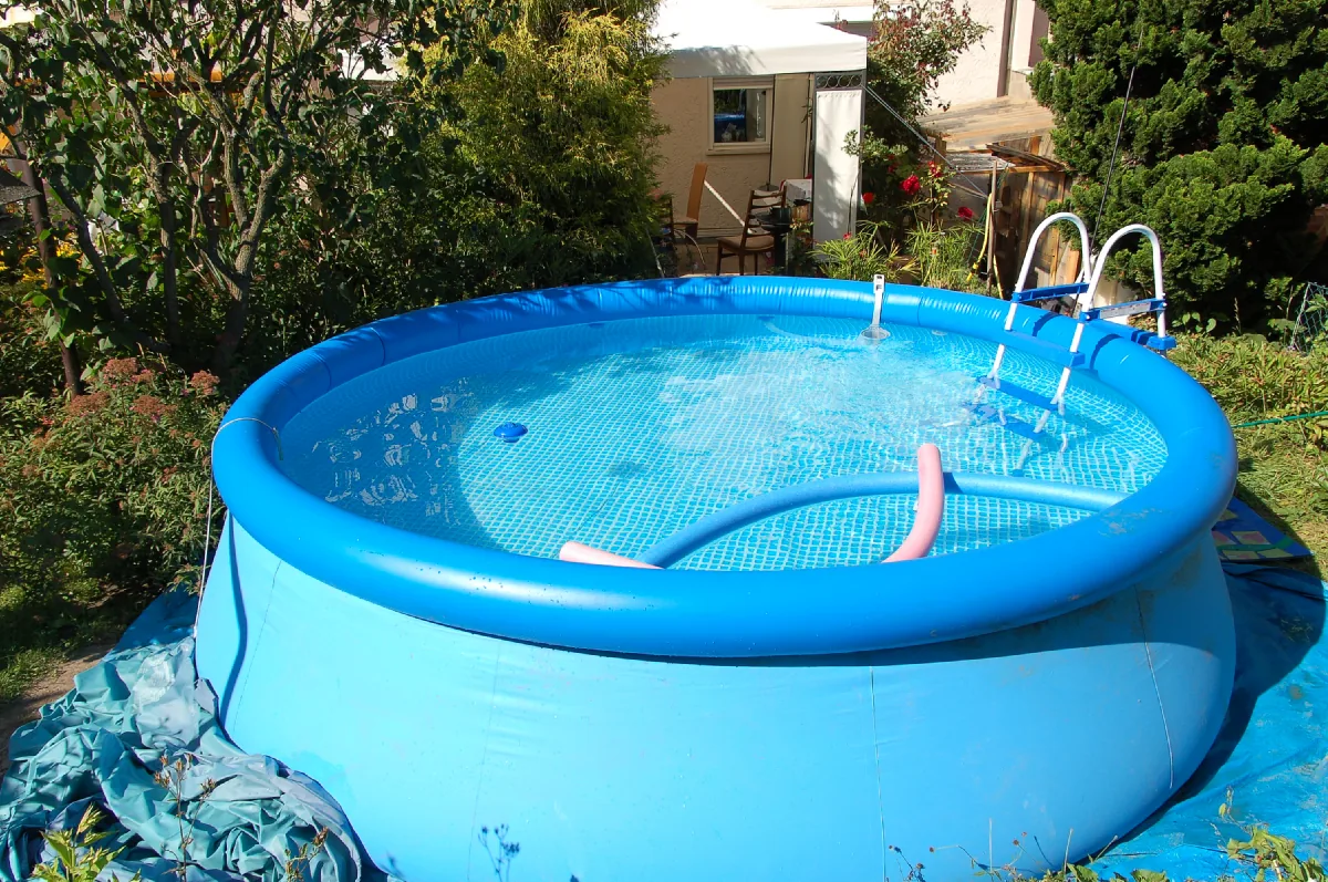Blue inflatable ring-top above-ground pool in a residential garden with ladder