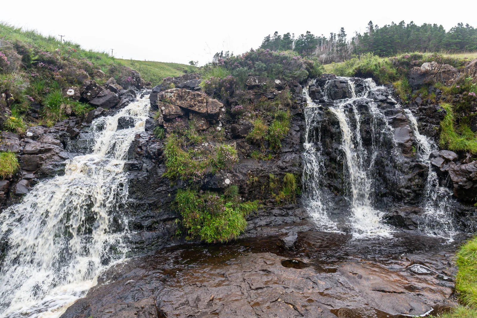Fairy Pools waterfall on the Isle of Skye with heather-covered banks and dark basalt rock, Skye Scotland
