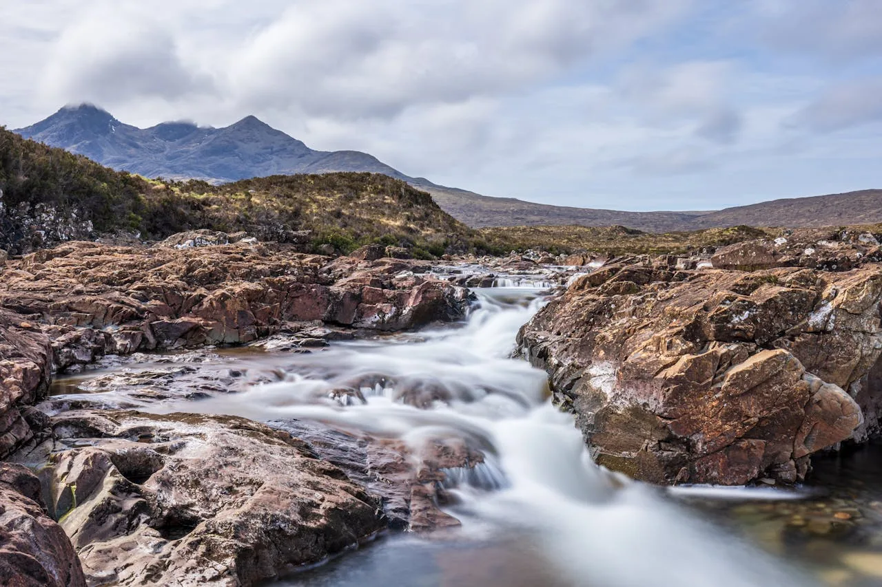The Fairy Pools on the Isle of Skye in golden morning light with turquoise water and the Black Cuillin mountains in the background representing the best time to visit the Fairy Pools including seasonal and time-of-day recommendations