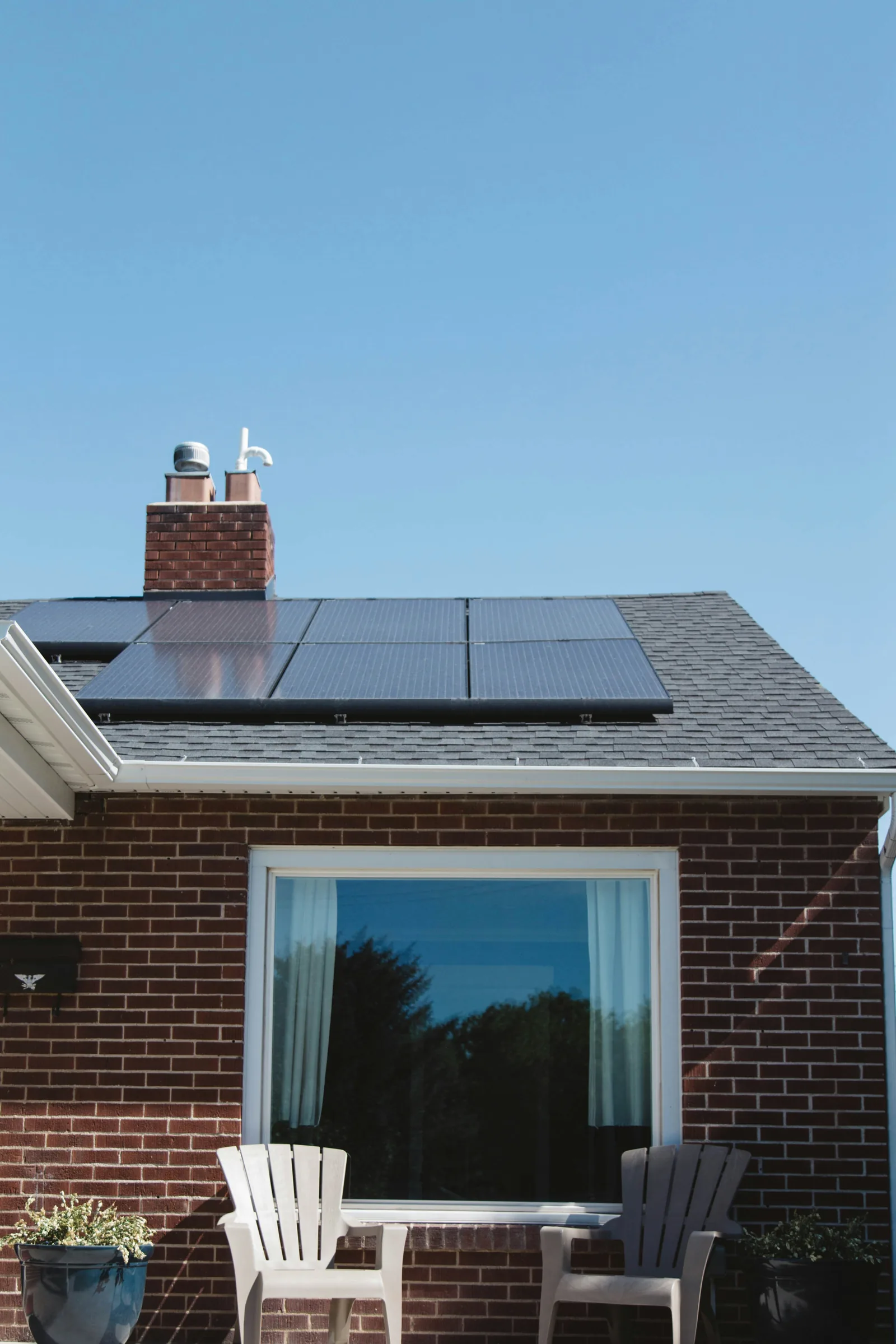 Brick house with solar PV panels installed on a south-facing roof under blue sky