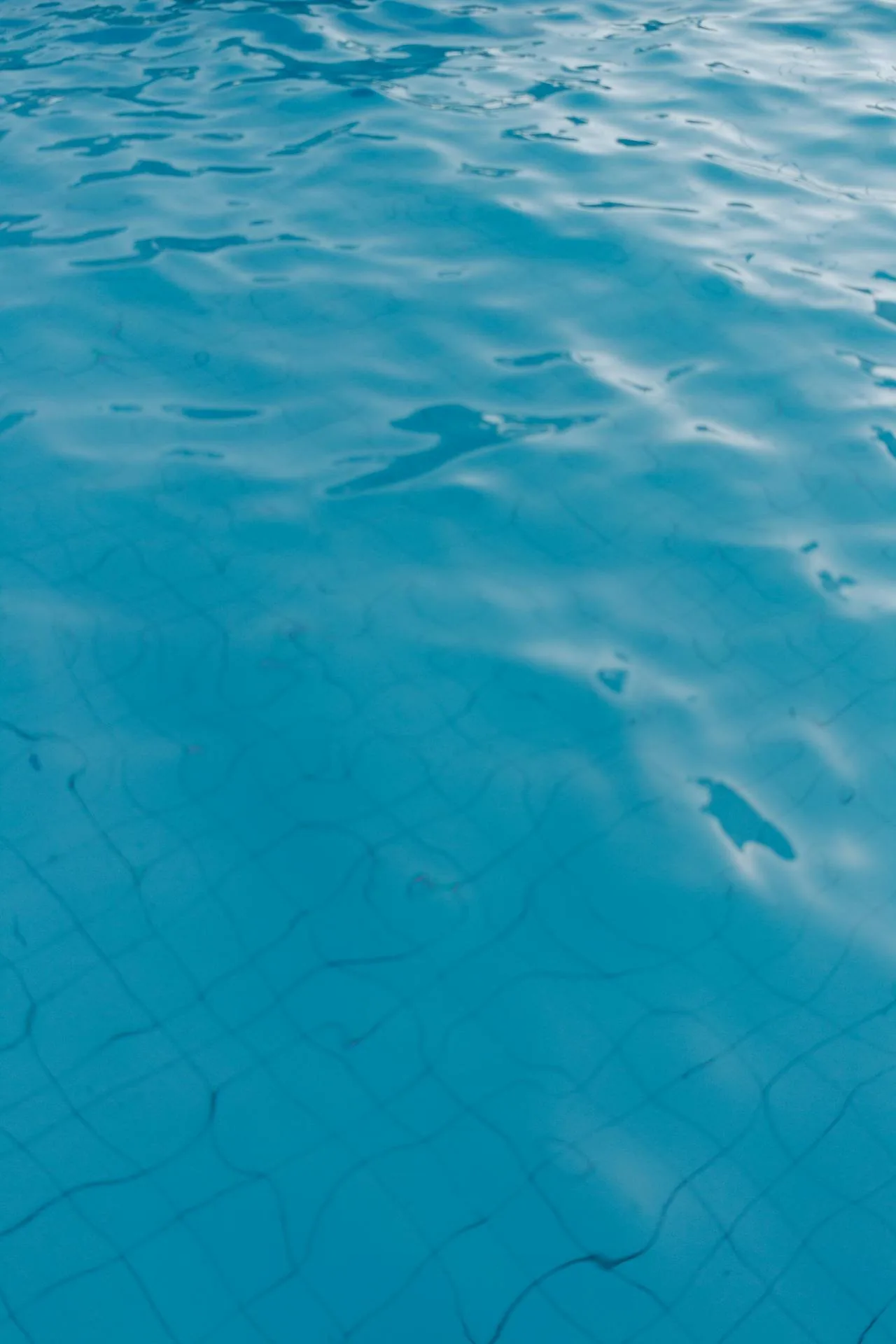 Close-up of clear turquoise pool water with shimmering light patterns representing clean well-treated swimming pool water and the alternatives to chlorine including PHMB UV systems and ozone treatment for UK pools