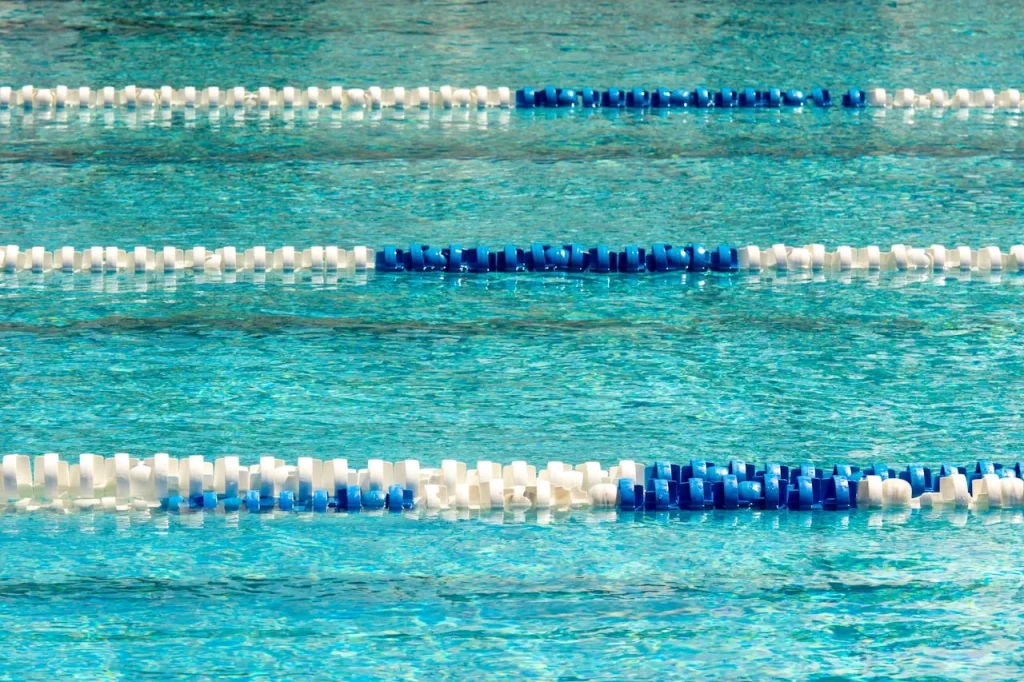 A crystal clear turquoise swimming pool with blue and white lane dividers representing correct chlorine levels pH balance and PWTAG water treatment standards for UK swimming pools