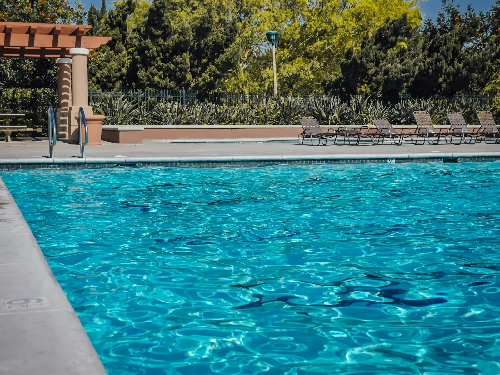 An outdoor swimming pool with a mechanical plant room and heating equipment representing pool heating systems in the UK including air source heat pumps solar thermal panels and gas boilers for domestic and hotel pools