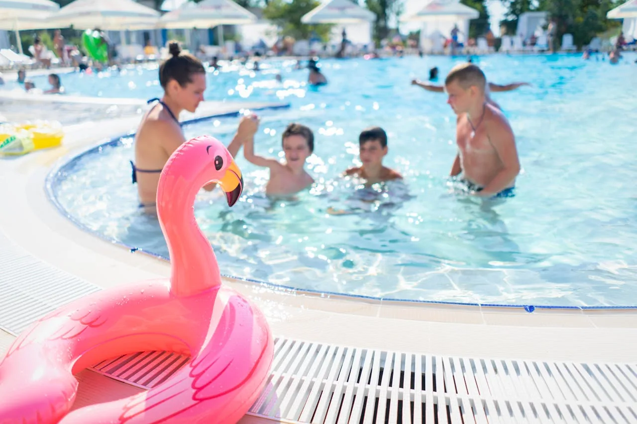 A family enjoying an outdoor above ground swimming pool with inflatable toys on a sunny day representing seasonal above ground metal frame and framed pool options for UK gardens