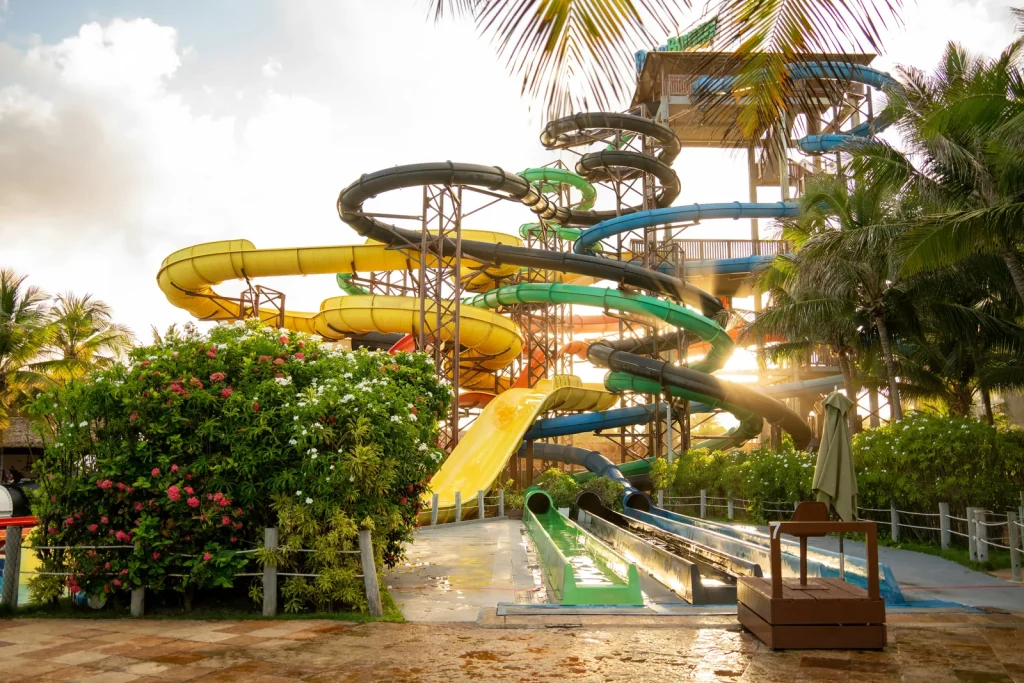 Multiple colourful water park flumes and slides at a leisure pool complex surrounded by palm trees