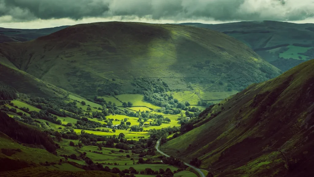 Remote moorland landscape in Wales with steep green hills and dramatic cloudy sky — the Teifi Pools sit in the Cambrian Mountains of Ceredigion at around 430 metres above sea level