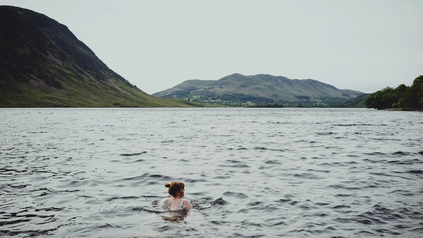 Wild swimmer in a remote mountain lake with hills and moorland in the background