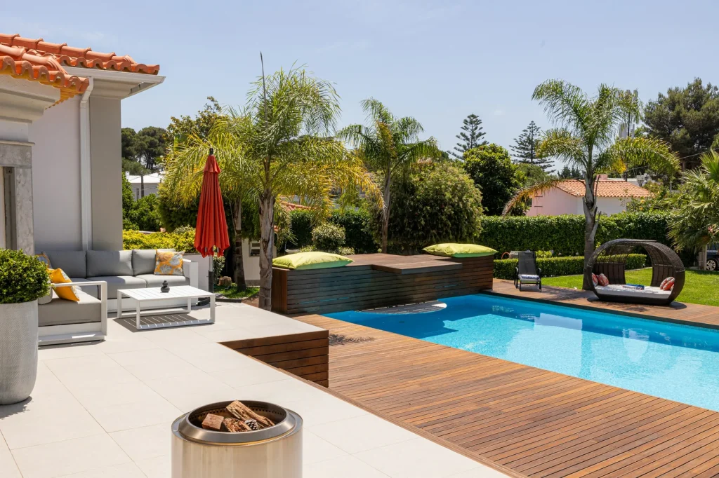 A beautifully landscaped garden with a rectangular in-ground swimming pool, wooden deck and outdoor seating